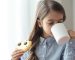 An elementary school girl is having breakfast with milk and funny cookies in the form of a smiley.